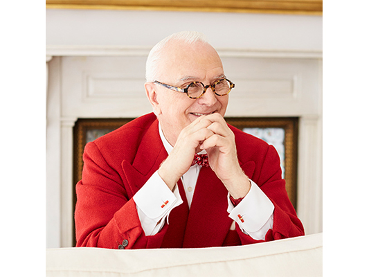 Manolo smiling in his characteristic red suit