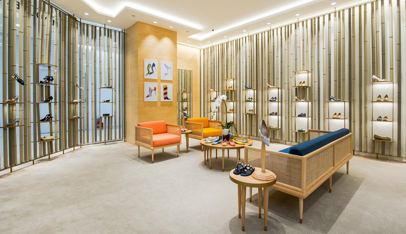 The inside of the Manolo Blahnik store in SOGO features sketches on the walls of the store, shoes displayed across various areas and a seating area with four chairs.